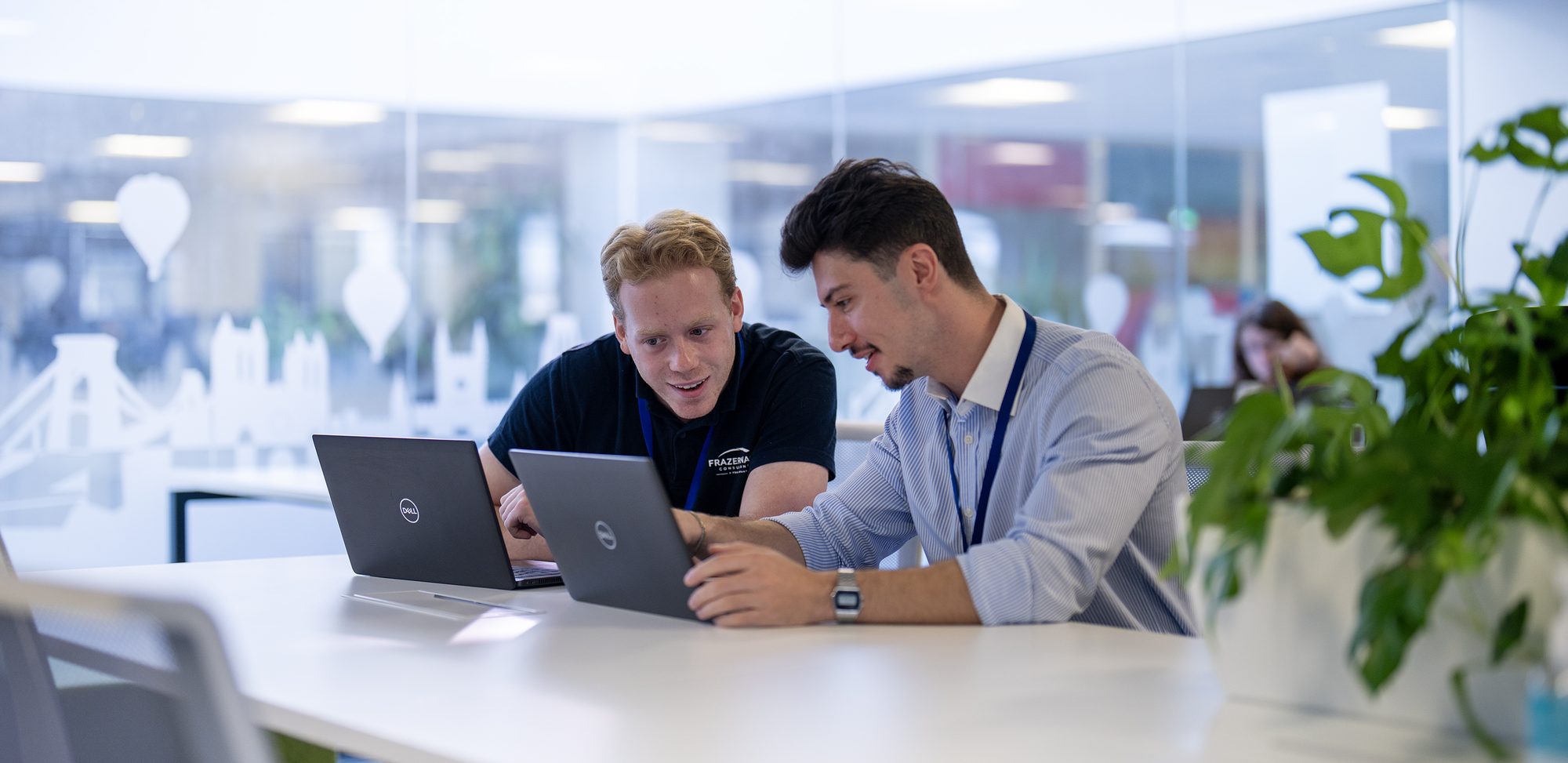 Frazer-Nash colleagues collaborating over laptops at the Bristol office